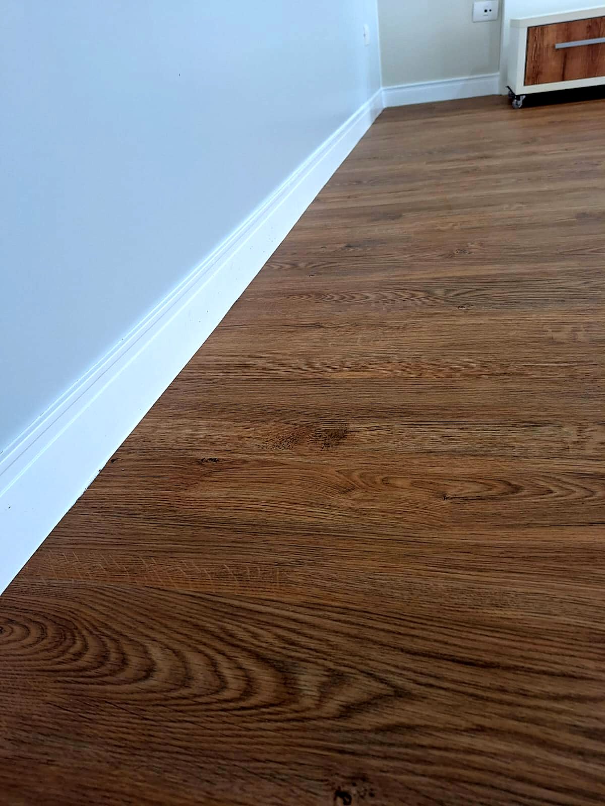 Rodapé branco alto com piso amadeirado